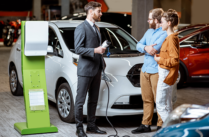 Photo of couple looking at a new EV car with salesman